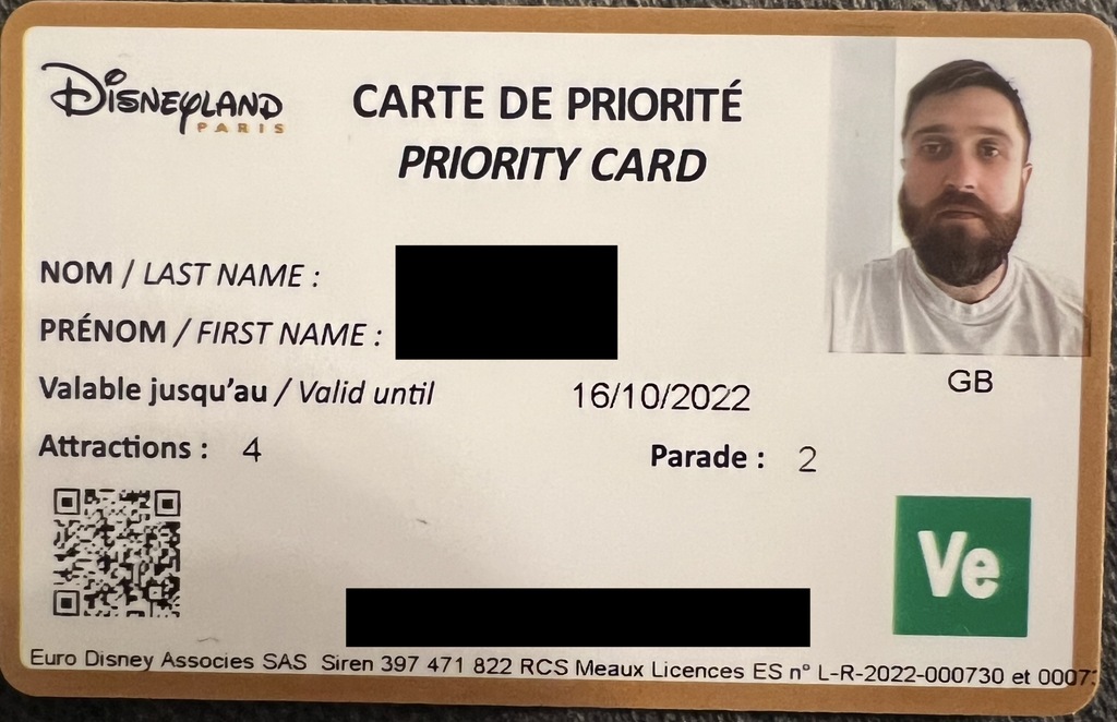 The front of a Disneyland Paris priority pass. On the top left is the Disneyland Paris Logo, along the top Carte De Priorité Priority Card, and on the top right is a photo of me with GB underneath it. In the middle of the card is Nom / Last name, Prénom / First name, Valable jusqu'ua / Valid until, Attractions: 4 and Parade 2. The bottom left has a QR code, the bottom right has a green box with Ve. It is bordered in gold.